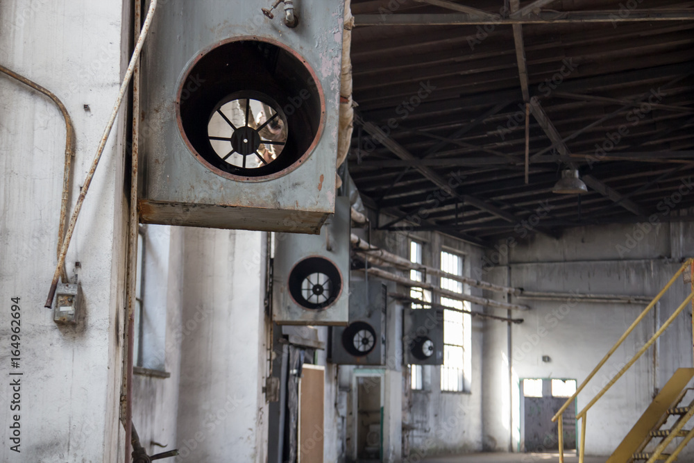 Interior of the old big abandoned factory, on the walls, broken air conditioning