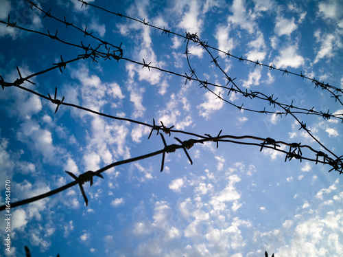Barbed wire against the sky with clouds