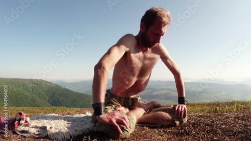 Blond Yogi in a Lotus Sharply Retracts the Belly on Top of a Mountain Under a Blue Sky
