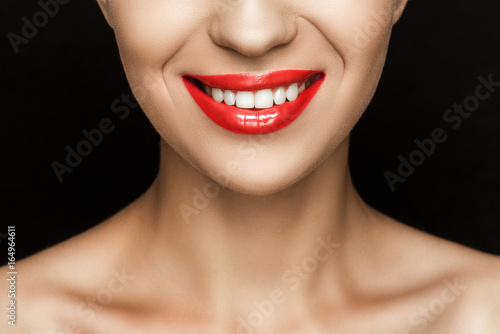 cropped view of gorgeous smiling woman with red lips, isolated on black
