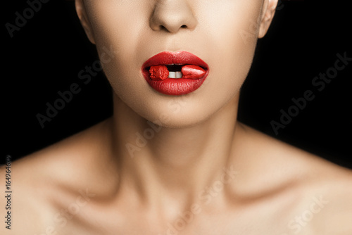 cropped view of seductive woman with red lipstick in mouth, isolated on black