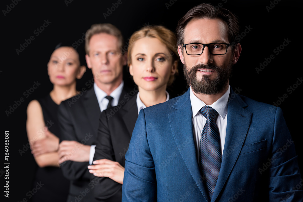 confident middle aged businesspeople standing with crossed arms and looking at camera isolated on black
