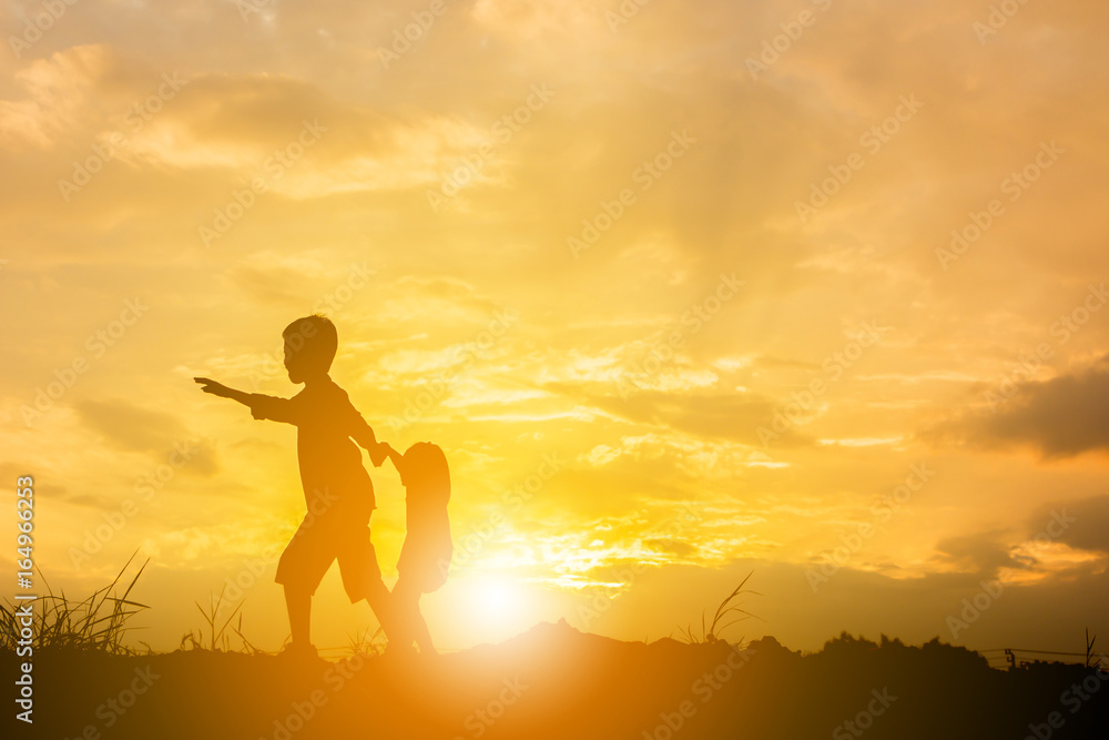 Silhouette of Boy and girl playing at sunset background, Happy children concept.