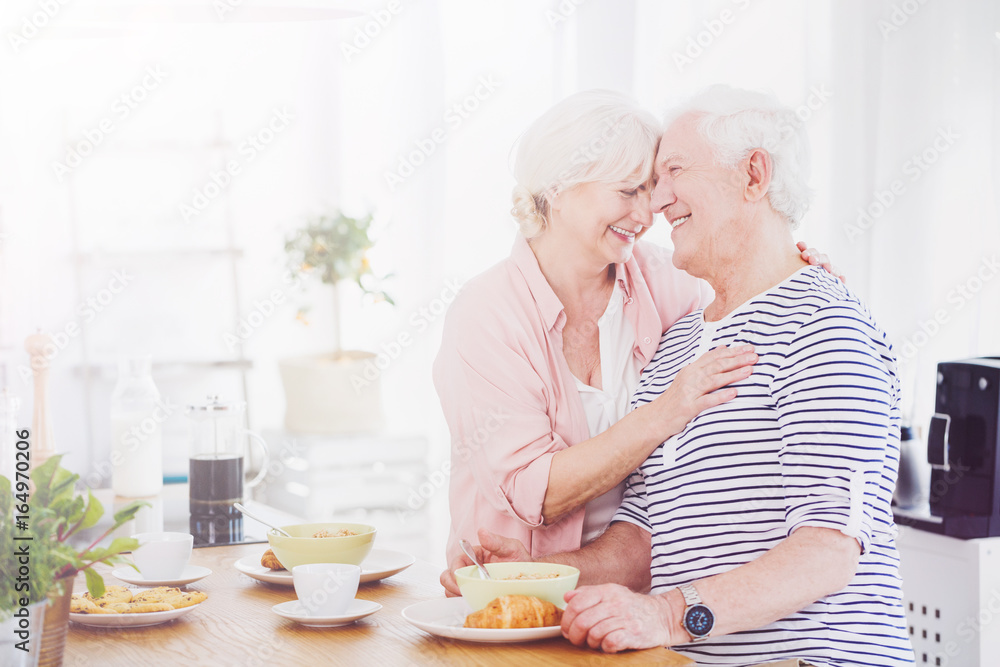 Elder man and woman hugging in the kitchen