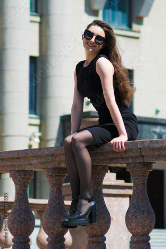 portrait of elegant woman in black dress walking in city