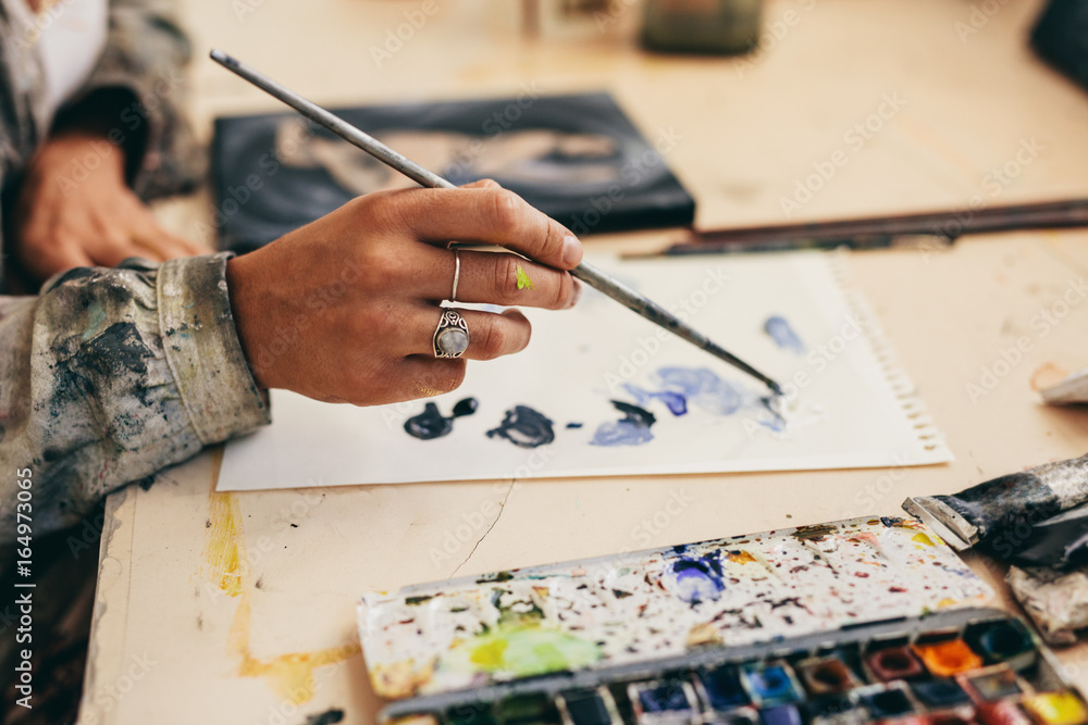 Obraz premium Female artist's hand mixing colors on paper