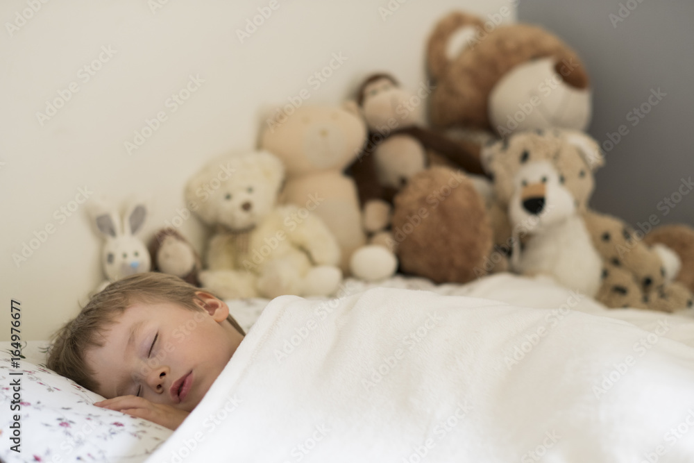 Sweet baby sleeping with his teddy bears in the background. Portrait with copy space.