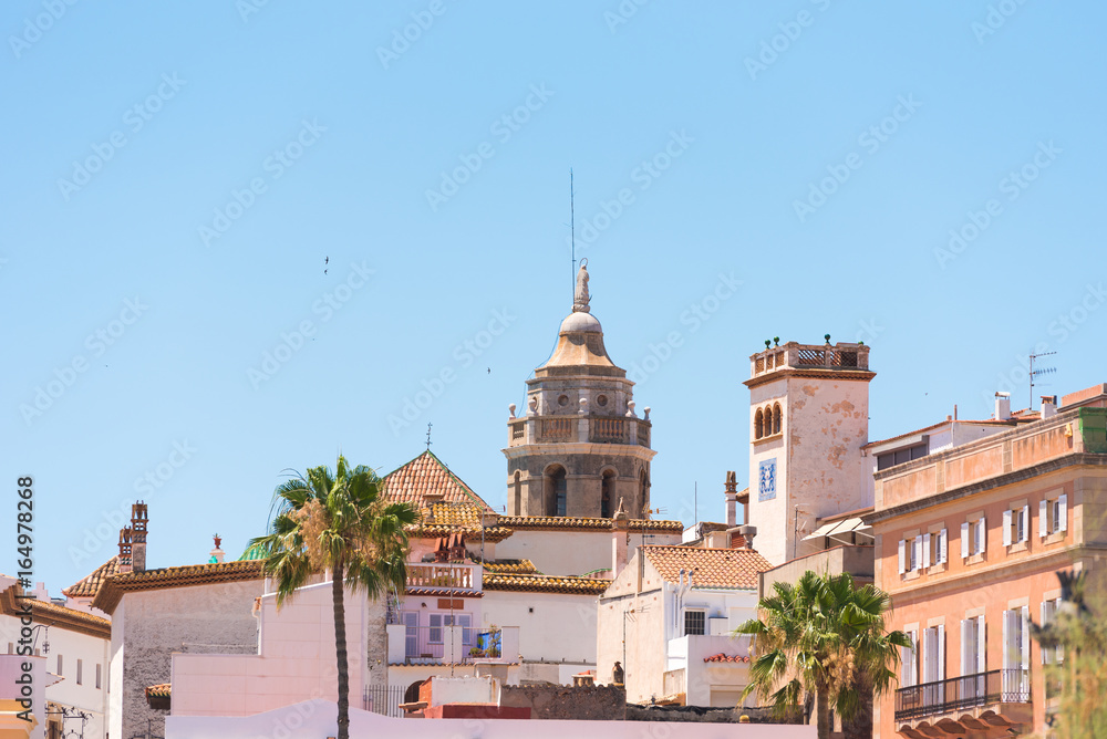 View of the historical center and the ñhurch of Sant Bartomeu and Santa Tecla in Sitges, Barcelona, Catalunya, Spain. Copy space for text. Isolated on blue background.