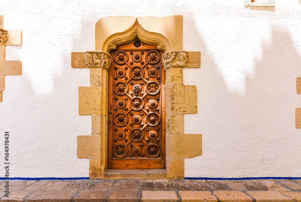 Naklejka premium The wooden door of the museum Marisel de Mar, Sitges, Barcelona, Catalunya, Spain. Ñopy space for text.
