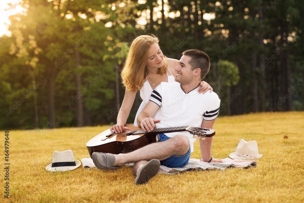 Young couple in love with guitar in nature