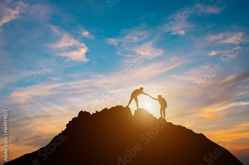  Silhouette of couple teamwork hiker helping each other on top of mountain
