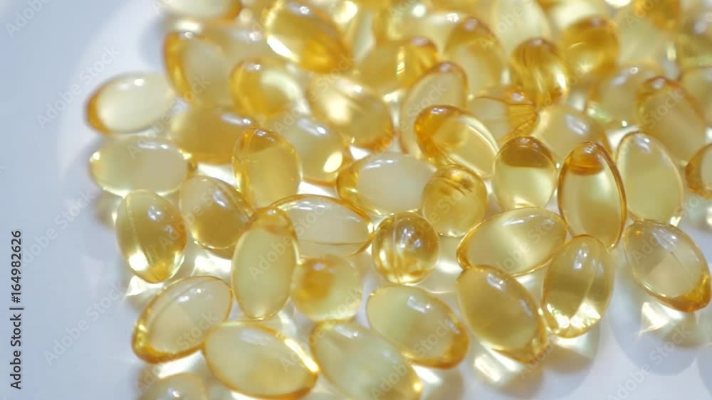 Pile of rice bran oil capsule pills supplementary product with omega 3 similar to fish oil is pouring into white isolated background. Fish oil omega 3 liquid gel capsules vitamin supplement closeup. Pile of rice bran oil capsule pills supplementary product with omega 3 similar to fish oil is pouring into white isolated background. Fish oil omega 3 liquid gel capsules vitamin supplement closeup.