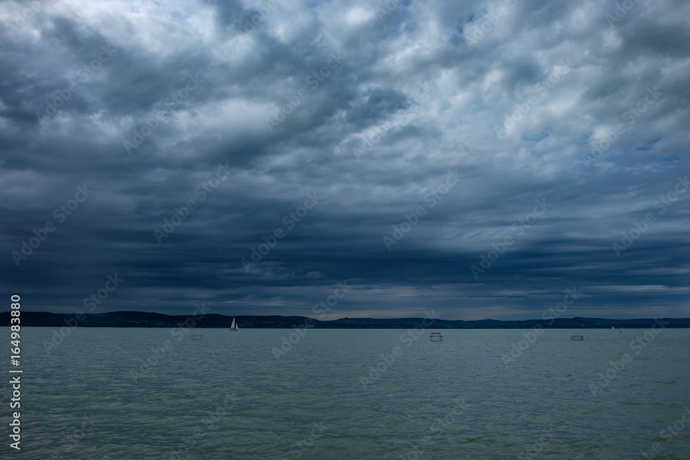 rain clouds over Balaton lake sailboat on the water - cold, cloudy, stormy weather in summer season
