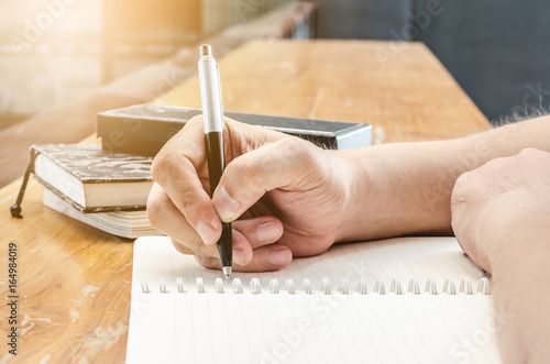 Close up of student hand writing on book with pen