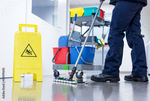 Worker janitor Mopping Floor In Office with trolley photo