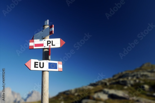Poland and European Union flag in two directions on road sign. Diplomatic crisis photo