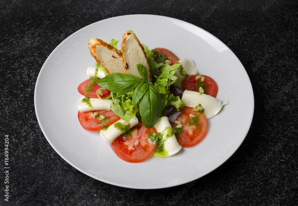 Salad with tomatoes basil and mozzarella with croutons on a white plate Salad with tomatoes basil and mozzarella with croutons on a white plate