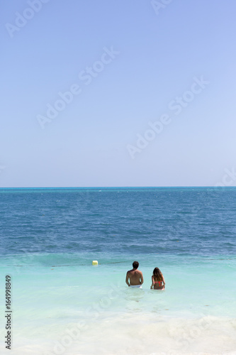Lovers on the sea. Couple standing on the ocean and thinking of swimming. Copy space. Vacation concept image.