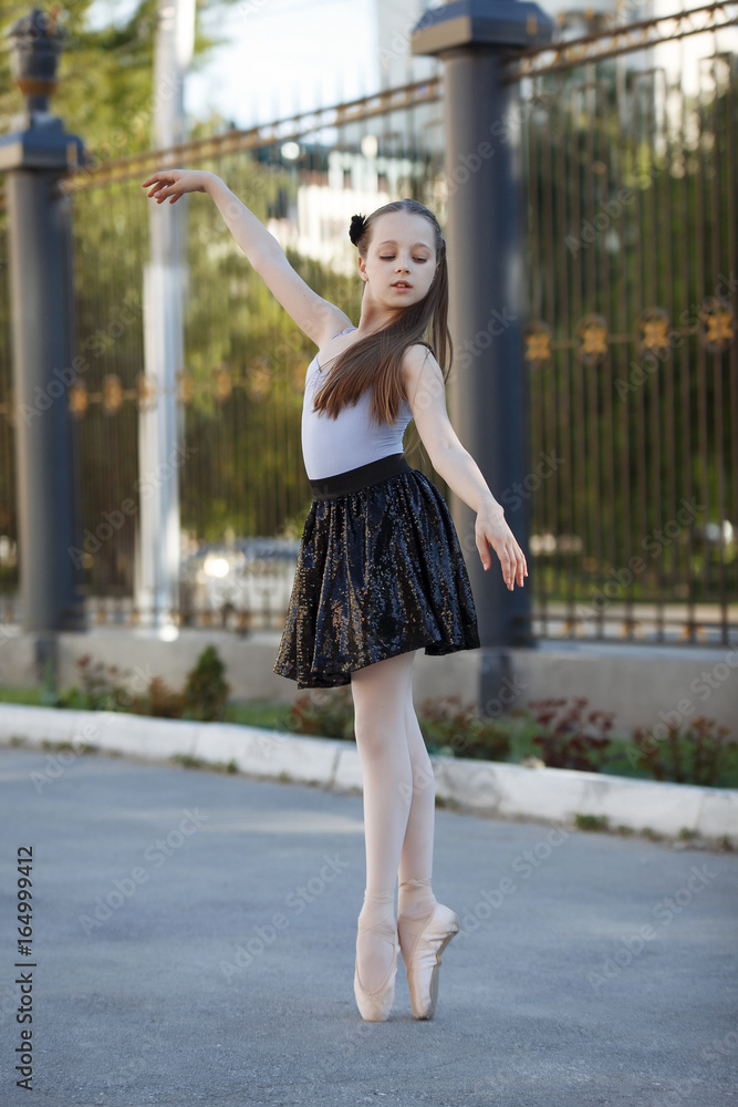 Young beautiful ballerina dancing outdoors in a park. Full length portrait beautiful caucasian girl.