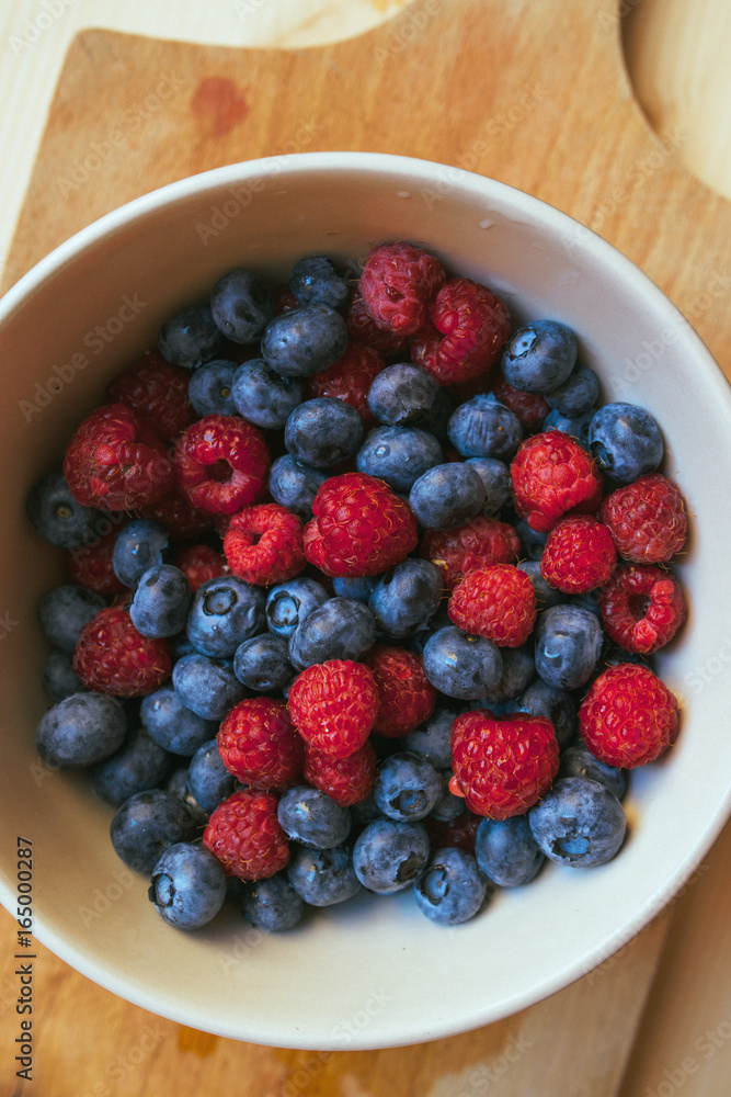 Blueberries and raspberries in white ceramic bowl Blueberries and raspberries in white ceramic bowl