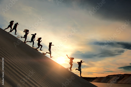 People running from the mountain at sunset