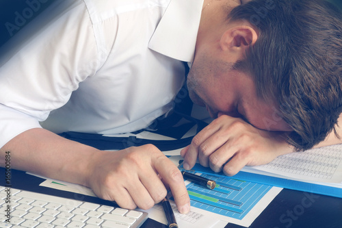 Chronic fatigue syndrome concept. Overworked businessman is sleeping at desk. photo