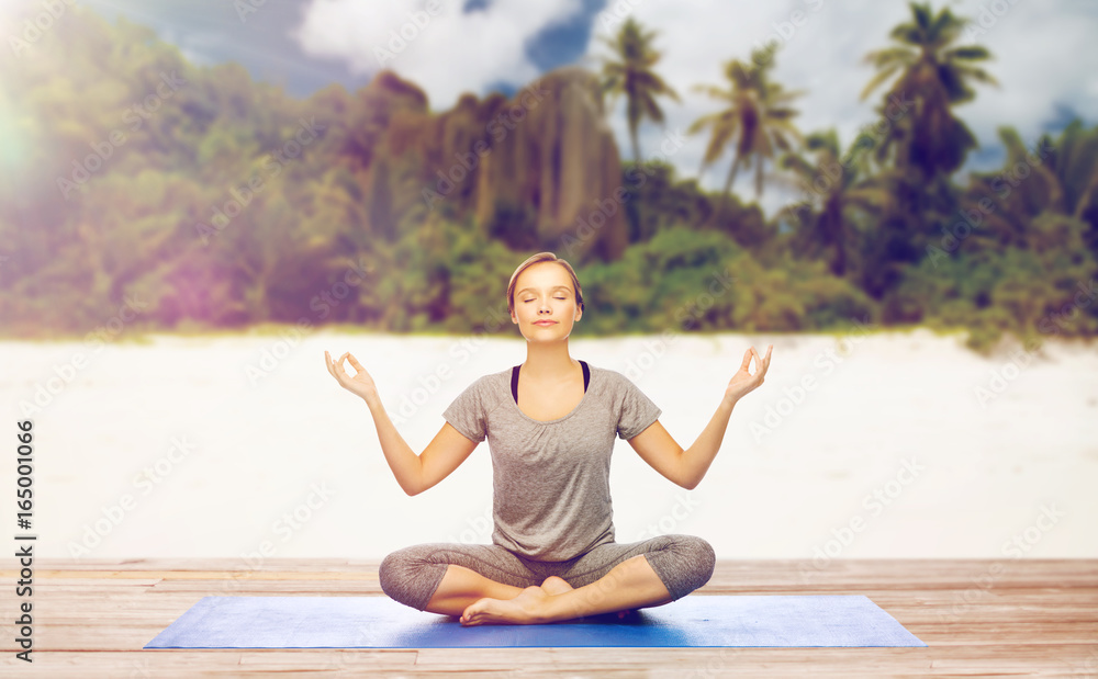 Fototapeta premium woman doing yoga meditation in lotus pose on beach