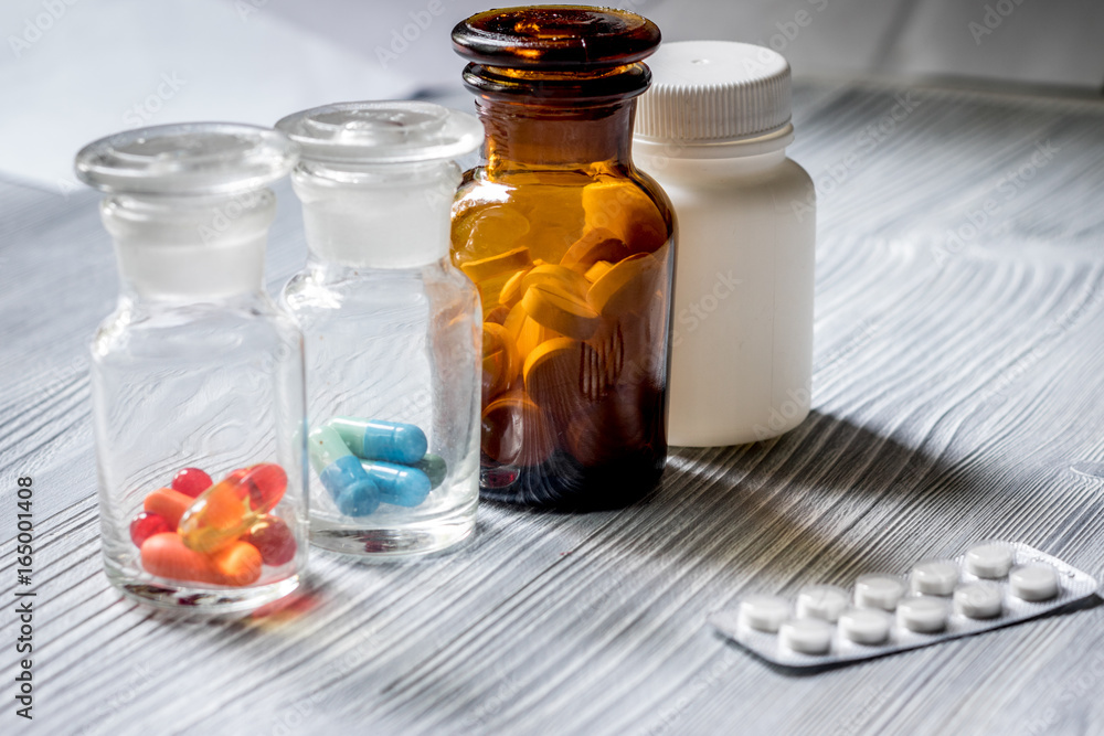 Vitamins and supplements. Pills and pill bottle on grey wooden table background Vitamins and supplements. Pills and pill bottle on grey wooden table background