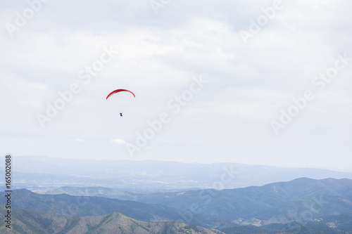 Paragliding in the sky. Paragliders fly over a mountain valley in summer sunny day.