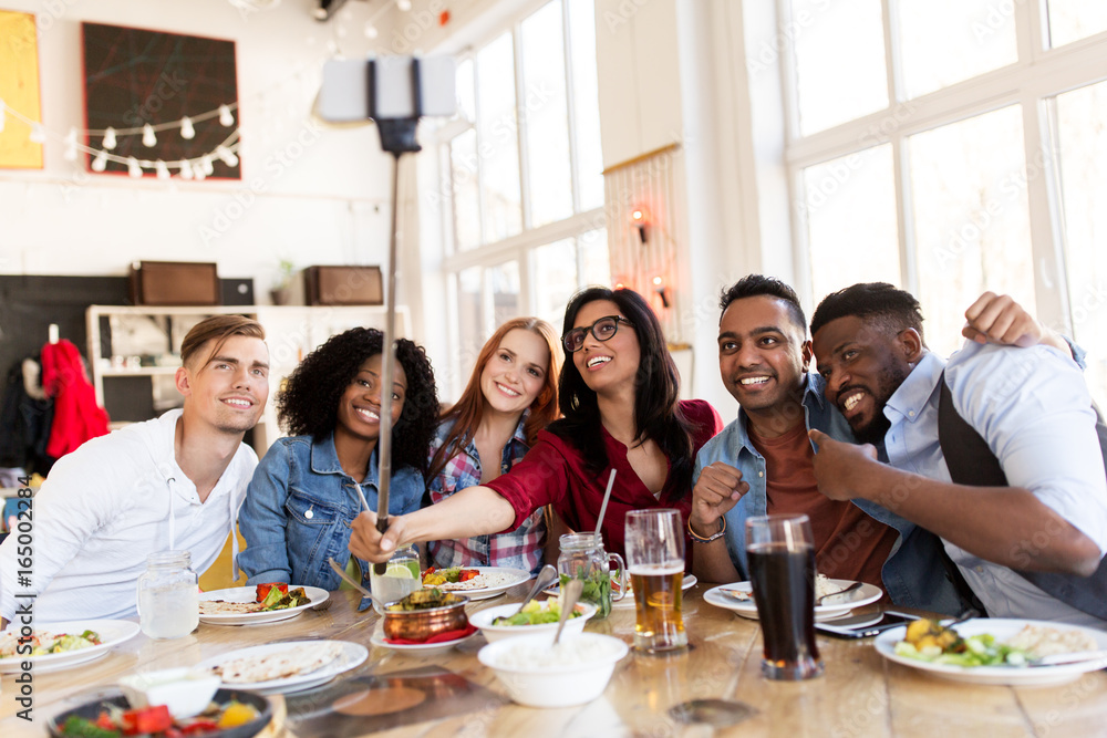 friends eating and taking selfie at restaurant