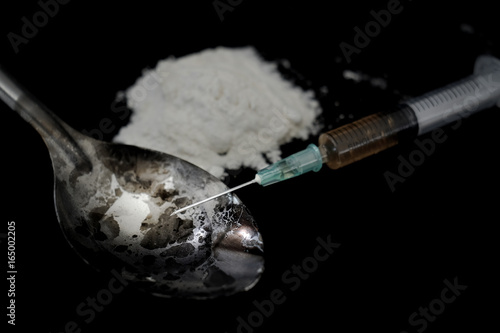 Drug syringe and cooked heroin on spoon