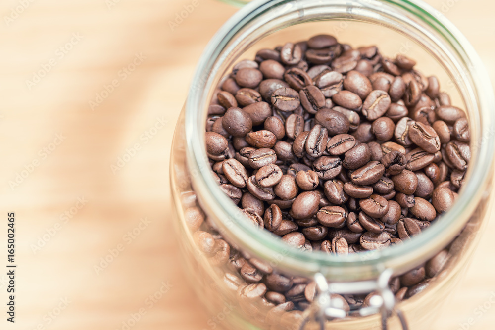 Coffee beans in glass jar on wooden background Coffee beans in glass jar on wooden background