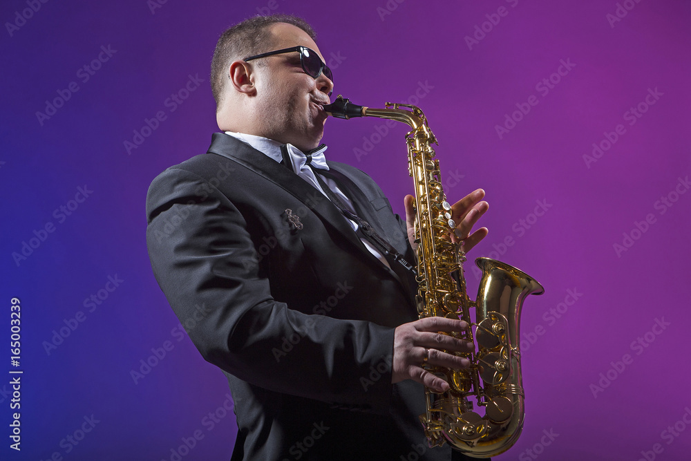 Fototapeta premium Singer plays the saxophone. Man. European. He plays the saxophone. Dressed in a suit.