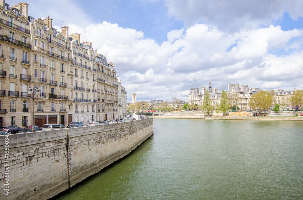 Seine River in Paris with the City Hall on the back and generic old historic parisian buildings on the front on a sunny spring day in this beautiful European city