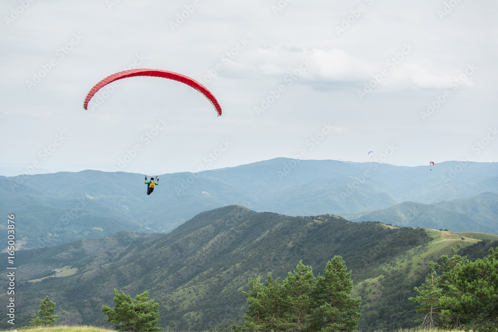 Paragliding in the sky. Paraglider flying over a mountain valley in summer sunny day. Paragliding in the sky. Paraglider flying over a mountain valley in summer sunny day.