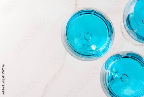 Alcohol drink. Glasses with trendy blue wine, on white marble table background. Copy space top view
