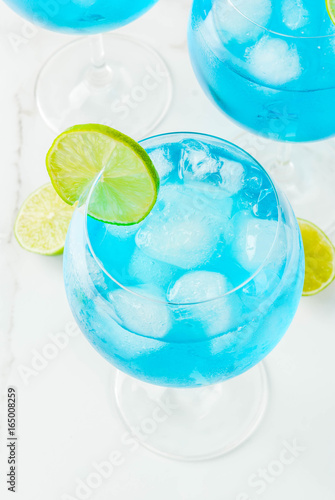 Alcohol drink. Glasses with a blue alcoholic cocktail with ice and lime garnish. Blue Curacao. Liquor. Copy space