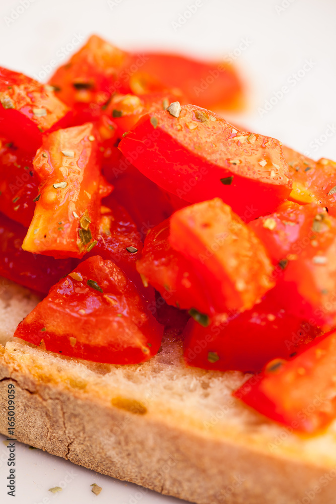 Tasty savory tomato Italian appetizers, or bruschetta, on slices of toasted baguette garnished with basil, close up on a wooden board Tasty savory tomato Italian appetizers, or bruschetta, on slices of toasted baguette garnished with basil, close up on a wooden board