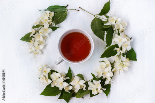 A Cup of black tea with fragrant Jasmine flowers on white background