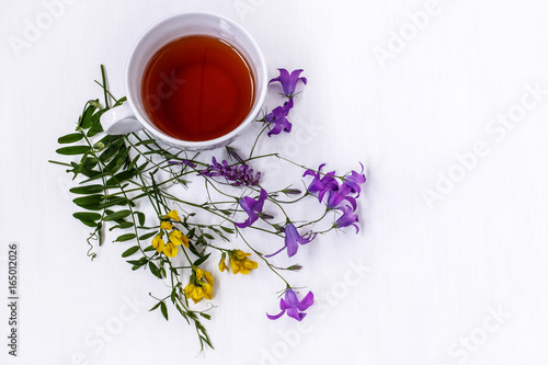 Cup of black tea with wild medicinal flowers on a white background