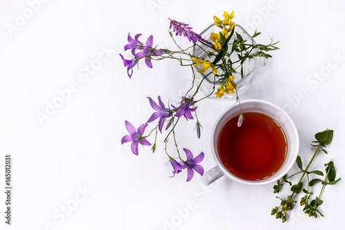 Cup of black tea with wild medicinal flowers on a white background photo