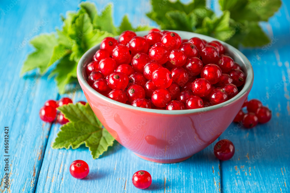 Fresh red currant in bowl on blue wooden background. Fresh red currant in bowl on blue wooden background.