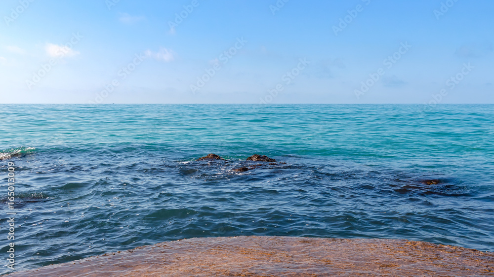 Fototapeta premium Seascape at black sea coast, on foreground stones in blue water at sunny summer day