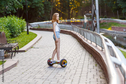 Happy girls riding on hover boards or gyroscooters outdoors at sunset in summer. Active life concept