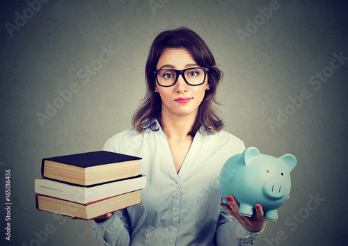 Принти на полотні woman with stack of books and piggy bank full of debt rethinking career path