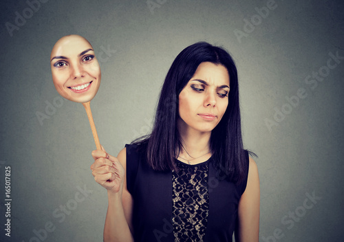woman with sad expression taking of a mask expressing cheerfulness