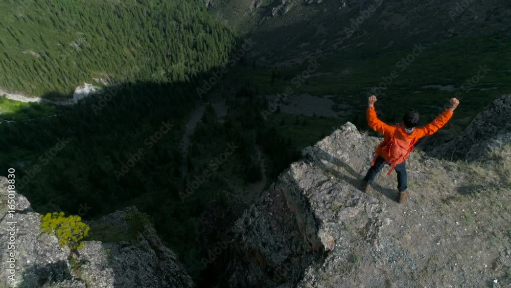 hiker at the top of a rock with his hands raised enjoy sunny day aerial slow motion 4k. hiker at the top of a rock with his hands raised enjoy sunny day aerial slow motion 4k.