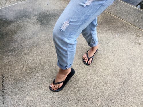Close Up on Girl's Feet Wearing Black Sandals and Blue Jeans on the Street Great For Any Use.