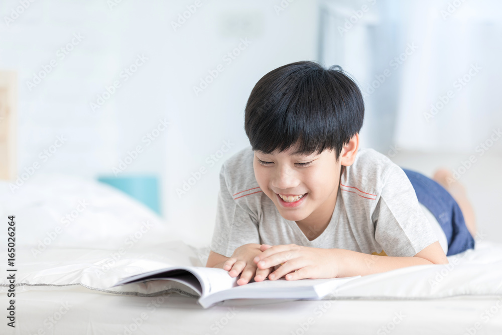 Happy Asian boy reading story book on the bed Happy Asian boy reading story book on the bed