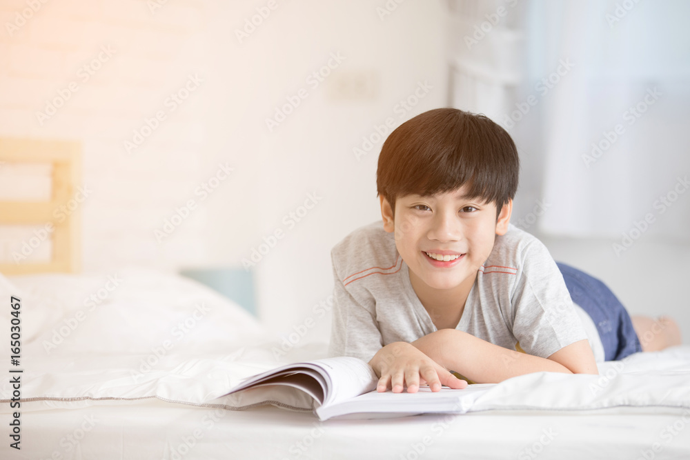 Happy Asian boy reading story book on the bed Happy Asian boy reading story book on the bed
